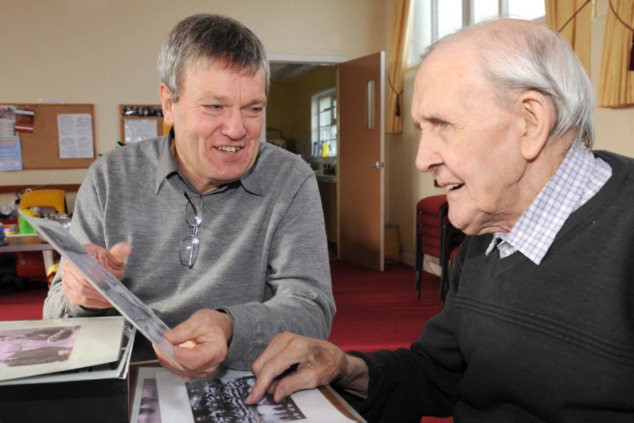 two men looking at old photgraphs of footballers | Courtesy of Michael White
