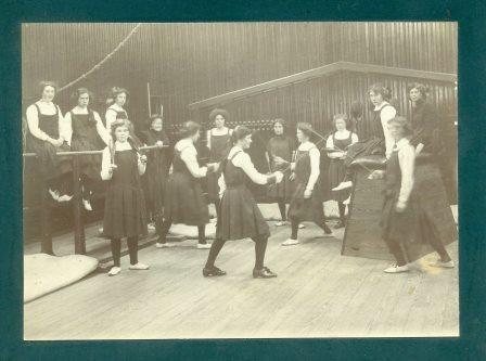 Picture of girls in gym class, featuring fencing and exercise clubs, 1911, Nicolson Institute, Stornaway | Museum nan Eilean