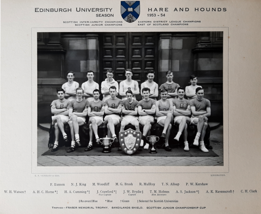 Black and white photo of Edinburgh University Hare and Hounds team, 1953-54. Team sat in two rows with their arms folded, trophies at their feet.The author’s father, T. M Holmes, is seated front row, fourth from right. Rest of team named beneath. | Courtesy of Terry Holmes