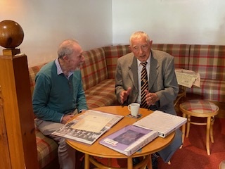 Two men chat and look at sporting memorabilia