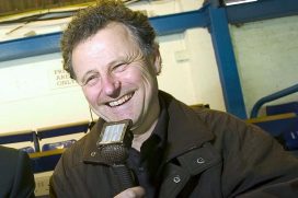 Mike Ingham smiling, holding mic while commentating