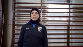 Dana Abdulkarim wearing a Hijab, stood in front of gym wall bars