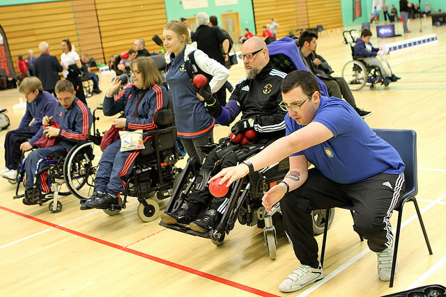 Group playing boccia, throwing balls. Some in wheelchairs. | Boccia England