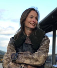 Head and torse shot of Karen Dobres wearing a leather coat and looking to the left.
