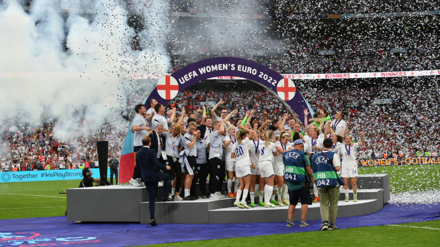Women's team on UEFA Women's EUROS 2022 podium. Fireworks, glitter and Wembley crowd in background. | Colorsport / Ashley Western