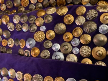 A close-up of the silver and gold metal buttons decorating the velvet purple cloak