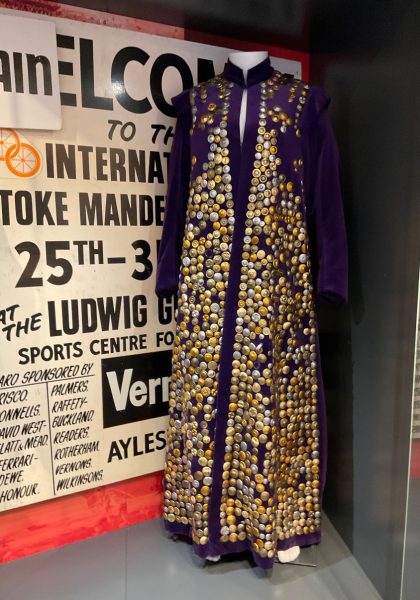 A full length photograph of the velvet purple cloak decorated with metal buttons on display at the NPHT