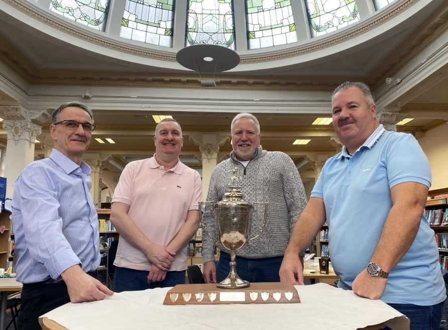 Four gentlemen standing behind a silver trophy in Rutherglen Library