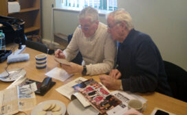 A group of men together looking at old photographs