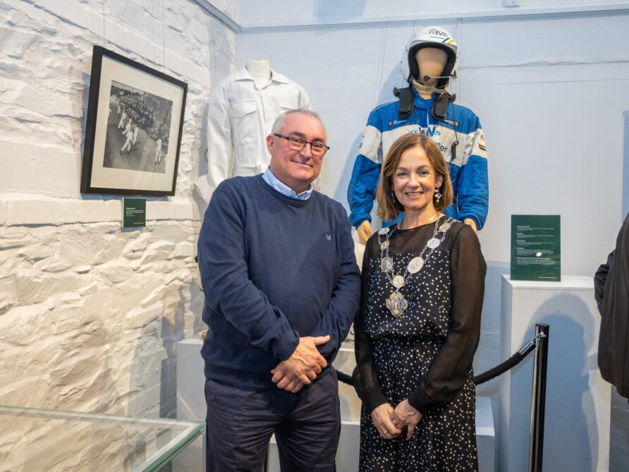 Graeme Stewart, Bangor rally driver and Mayor of Ards and North Down Mayor of Ards and North Down, Councillor Gillian McCollum with Graeme Stewart, Bangor rally driver standing in front of his racing overalls that he kindly loaned to the museum for the exhibition. | Ards and North Down Borough Council